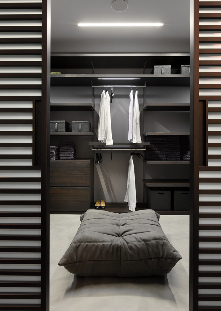 This is an example of a contemporary gender-neutral dressing room in Other with flat-panel cabinets and dark wood cabinets.