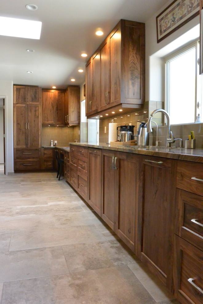 Huge transitional l-shaped porcelain tile and gray floor open concept kitchen photo with an undermount sink, shaker cabinets, medium tone wood cabinets, quartzite countertops, white backsplash, porcelain backsplash, paneled appliances, an island and green countertops