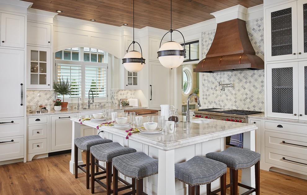 Design ideas for a mid-sized beach style kitchen with a farmhouse sink, white cabinets, marble benchtops, multi-coloured splashback, stainless steel appliances, medium hardwood floors, with island, shaker cabinets, mosaic tile splashback and beige benchtop.