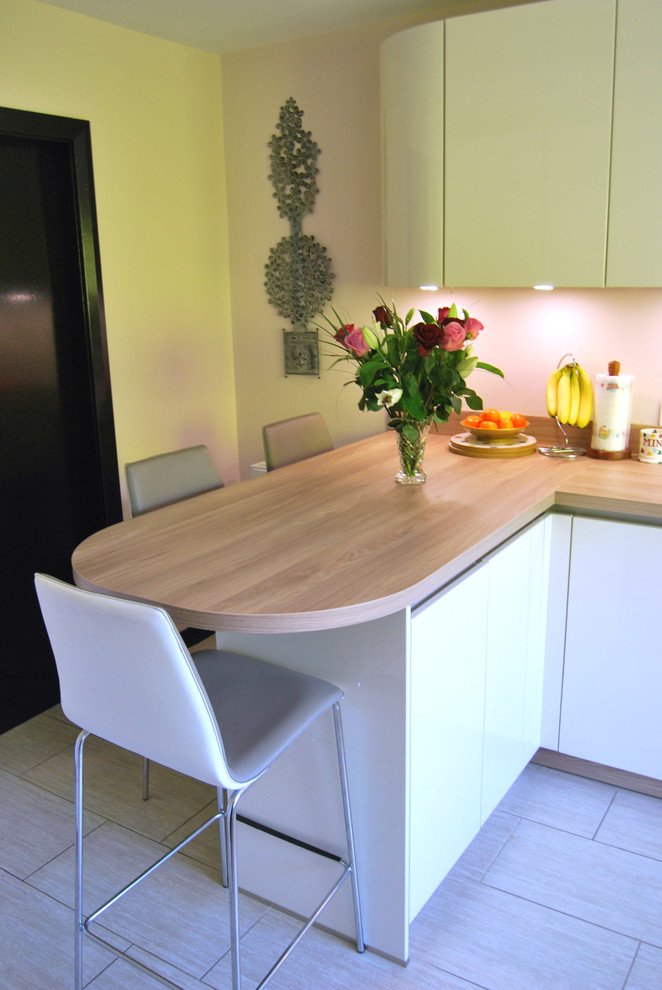 Design ideas for a small contemporary u-shaped eat-in kitchen in Cheshire with flat-panel cabinets, white cabinets, laminate benchtops, grey splashback, glass sheet splashback and a peninsula.