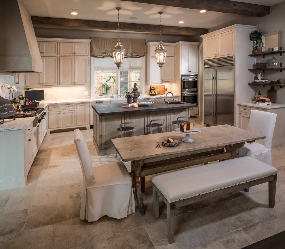This is an example of a large traditional u-shaped eat-in kitchen in Houston with a farmhouse sink, recessed-panel cabinets, white cabinets, quartzite benchtops, white splashback, limestone splashback, stainless steel appliances, limestone floors, with island and beige floor.