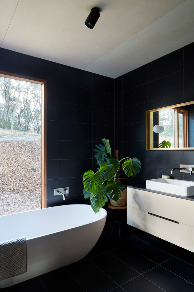Contemporary master bathroom in Other with flat-panel cabinets, white cabinets, a freestanding tub, black tile, a vessel sink and black floor.