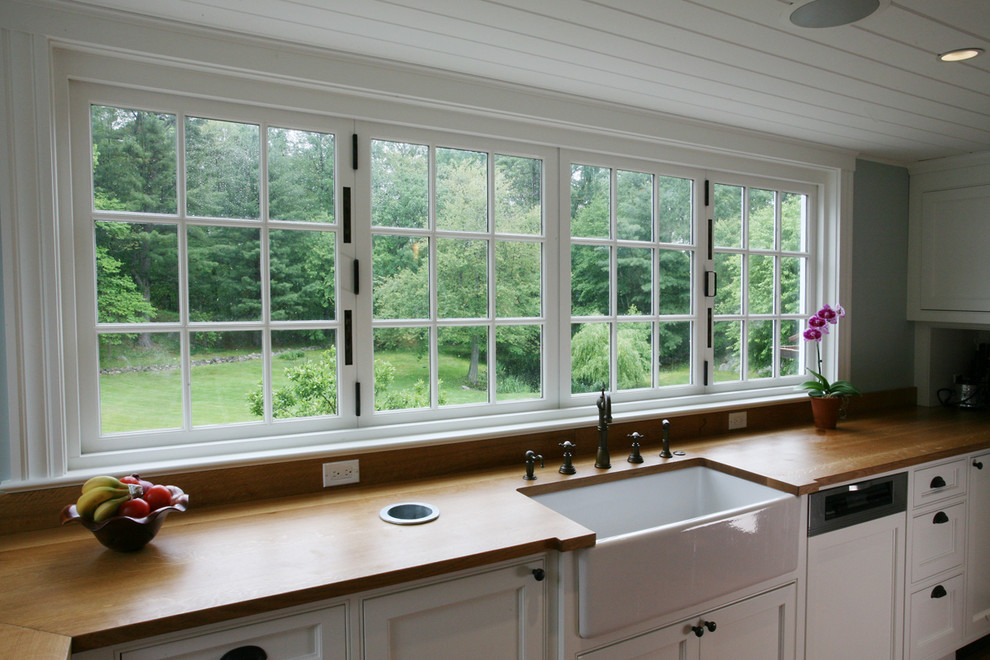 Photo of a country eat-in kitchen in Boston with a drop-in sink, flat-panel cabinets, white cabinets, wood benchtops, white appliances and dark hardwood floors.