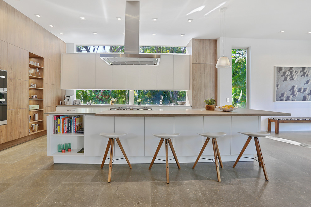 Photo of a large contemporary galley open plan kitchen in Miami with flat-panel cabinets, white cabinets, with island, an undermount sink, concrete benchtops, window splashback, panelled appliances and concrete floors.