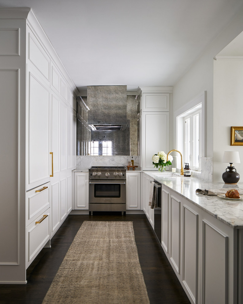 Example of a small transitional u-shaped dark wood floor and brown floor enclosed kitchen design in Chicago with an undermount sink, raised-panel cabinets, white cabinets, marble countertops, white backsplash, mirror backsplash, stainless steel appliances, a peninsula and white countertops