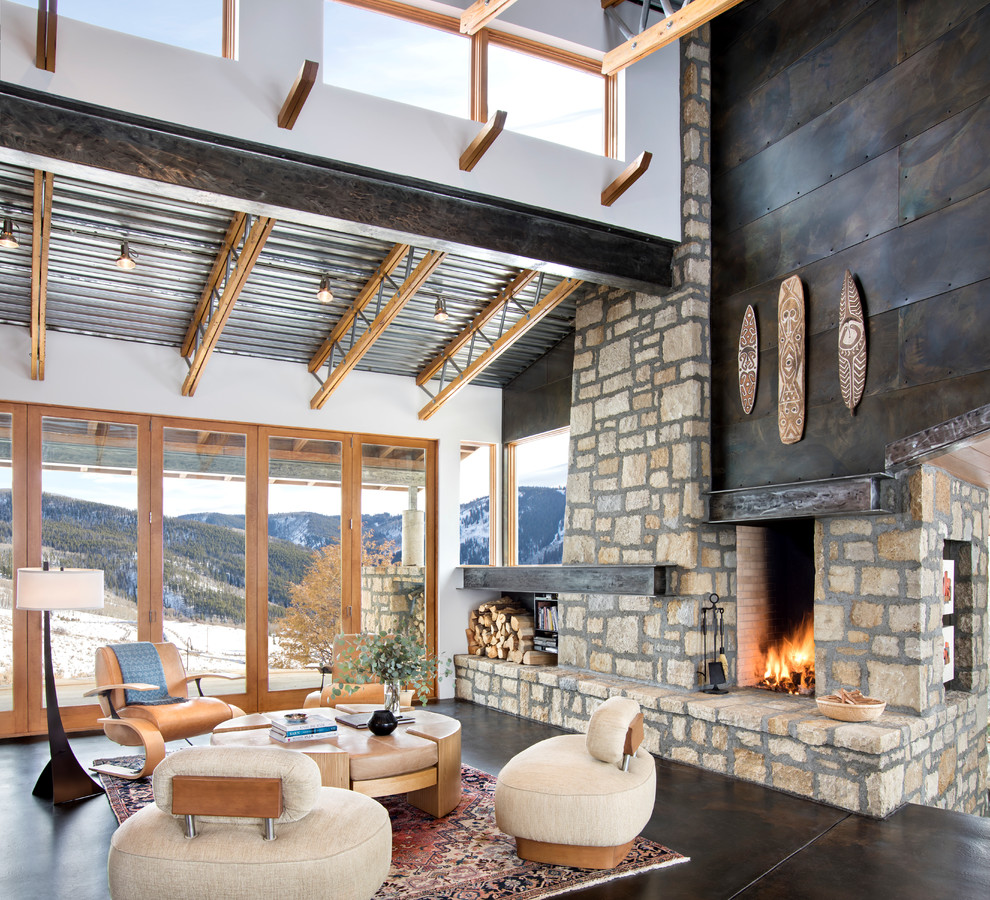 Inspiration for a large industrial living room in Denver with white walls, concrete floors, a standard fireplace, a stone fireplace surround and brown floor.