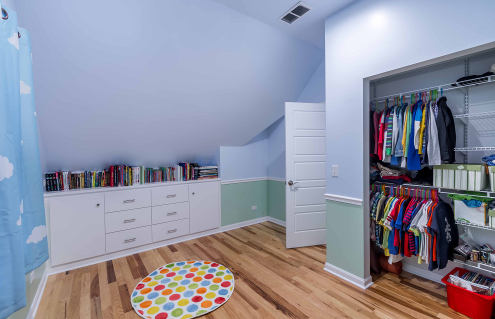 Ejemplo de armario vestidor unisex tradicional de tamaño medio con armarios con paneles lisos, puertas de armario blancas, suelo de madera clara, suelo marrón y papel pintado