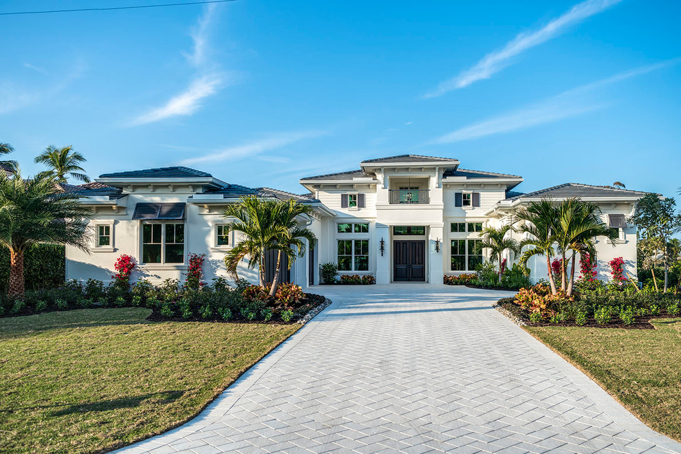 Large beach style two-storey stucco beige house exterior in Other with a hip roof and a tile roof.