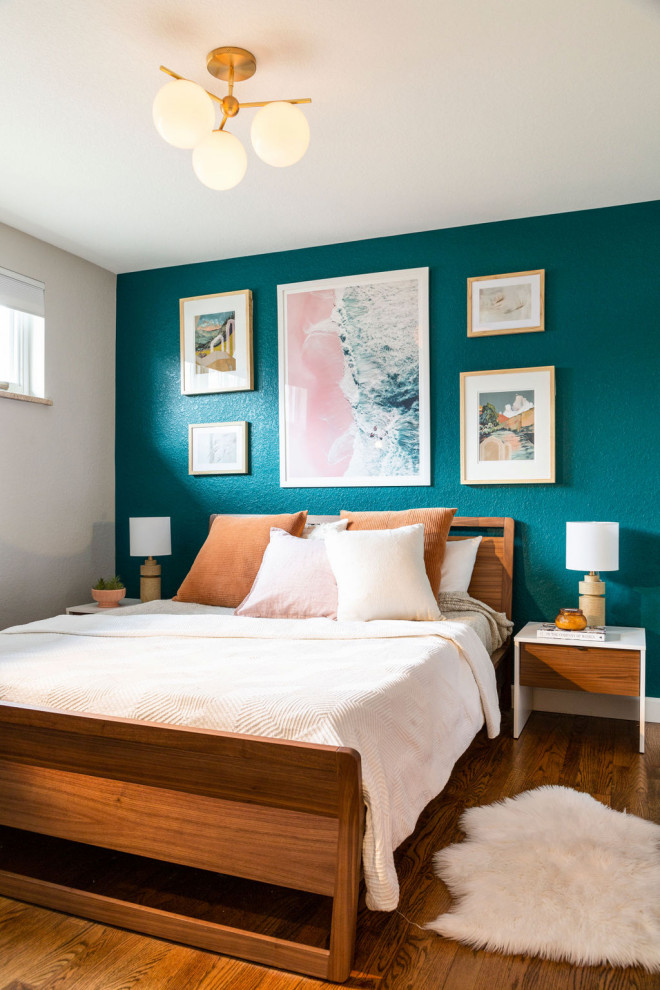 This is an example of a mid-sized beach style master bedroom in Denver with blue walls, medium hardwood floors, no fireplace and brown floor.