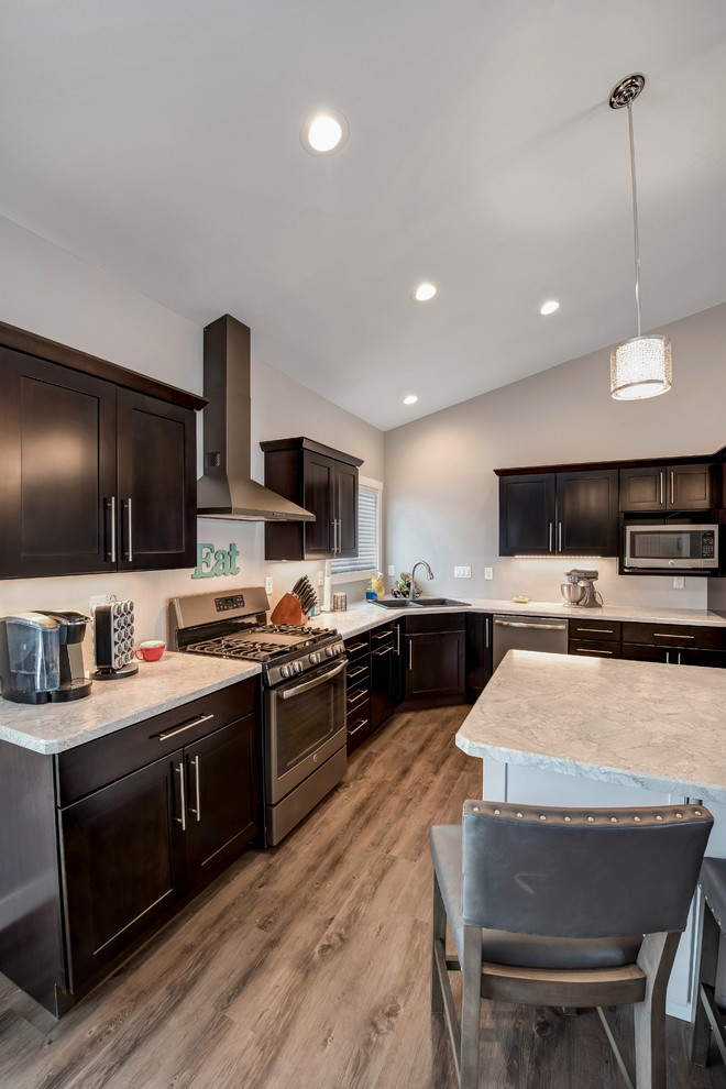 Example of a large transitional l-shaped medium tone wood floor open concept kitchen design with a double-bowl sink, shaker cabinets, dark wood cabinets, quartzite countertops, stainless steel appliances and an island