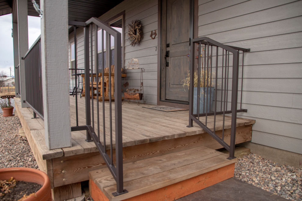 Inredning av en mellanstor veranda framför huset, med stämplad betong, markiser och räcke i metall