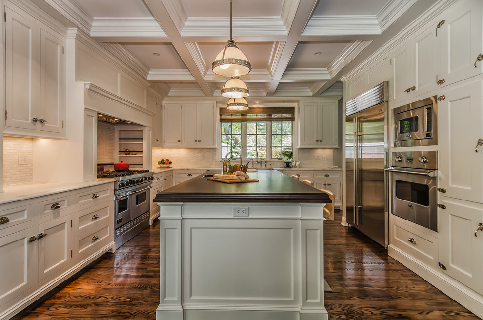 This is an example of a traditional u-shaped separate kitchen in New York with shaker cabinets, white cabinets, white splashback, stainless steel appliances, dark hardwood floors and with island.
