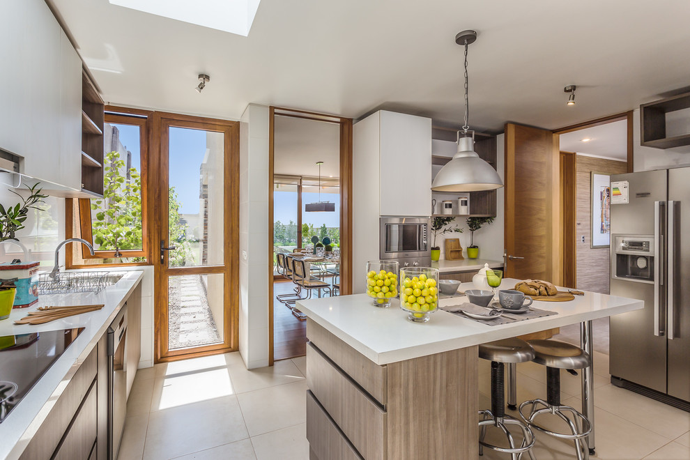 Photo of a contemporary u-shaped separate kitchen in Madrid with a single-bowl sink, flat-panel cabinets, medium wood cabinets, white splashback, stainless steel appliances, with island, white benchtop and beige floor.