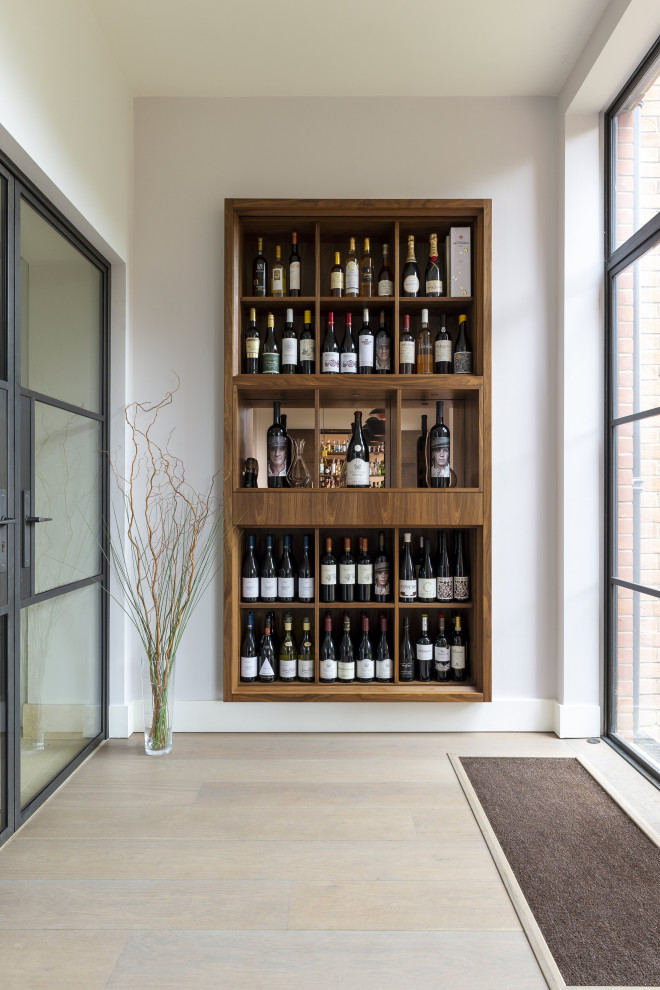 Photo of a mid-sized contemporary wine cellar in London with medium hardwood floors, display racks and beige floor.