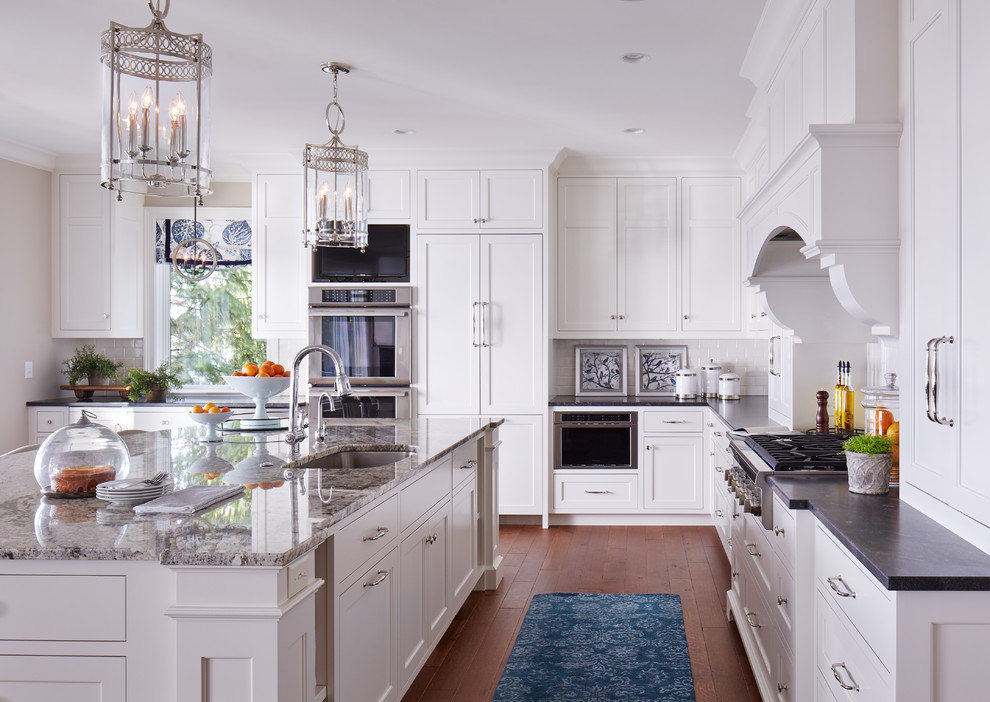 Inspiration for a large traditional galley eat-in kitchen in Minneapolis with an undermount sink, recessed-panel cabinets, white cabinets, white splashback, stainless steel appliances, medium hardwood floors and with island.