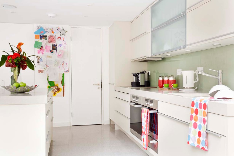 Inspiration for a mid-sized contemporary galley eat-in kitchen in Surrey with an undermount sink, flat-panel cabinets, beige cabinets, green splashback, glass sheet splashback, stainless steel appliances and with island.