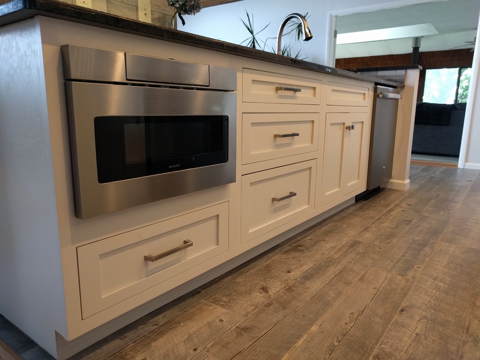 Design ideas for a mid-sized transitional galley separate kitchen in Philadelphia with an undermount sink, shaker cabinets, white cabinets, granite benchtops, grey splashback, porcelain splashback, stainless steel appliances, medium hardwood floors, no island, brown floor and black benchtop.