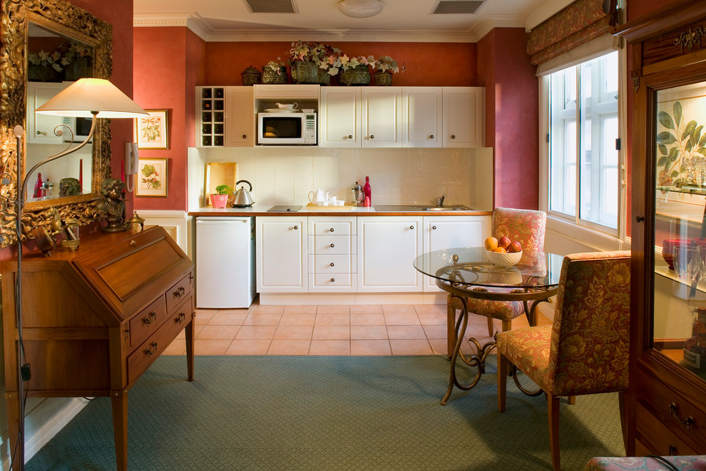 Photo of a mid-sized traditional galley eat-in kitchen in Other with raised-panel cabinets, white cabinets, white splashback, white appliances, a drop-in sink, concrete benchtops and with island.