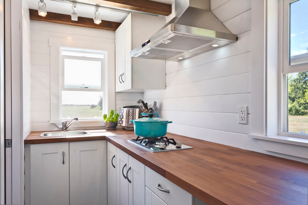 Small beach style l-shaped kitchen in Vancouver with a drop-in sink, flat-panel cabinets, white cabinets, wood benchtops, stainless steel appliances, dark hardwood floors, no island and shiplap splashback.
