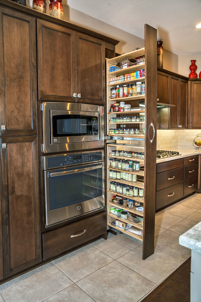 Example of a transitional ceramic tile eat-in kitchen design in Phoenix with an undermount sink, recessed-panel cabinets, dark wood cabinets, quartzite countertops, gray backsplash, stone tile backsplash, stainless steel appliances and an island