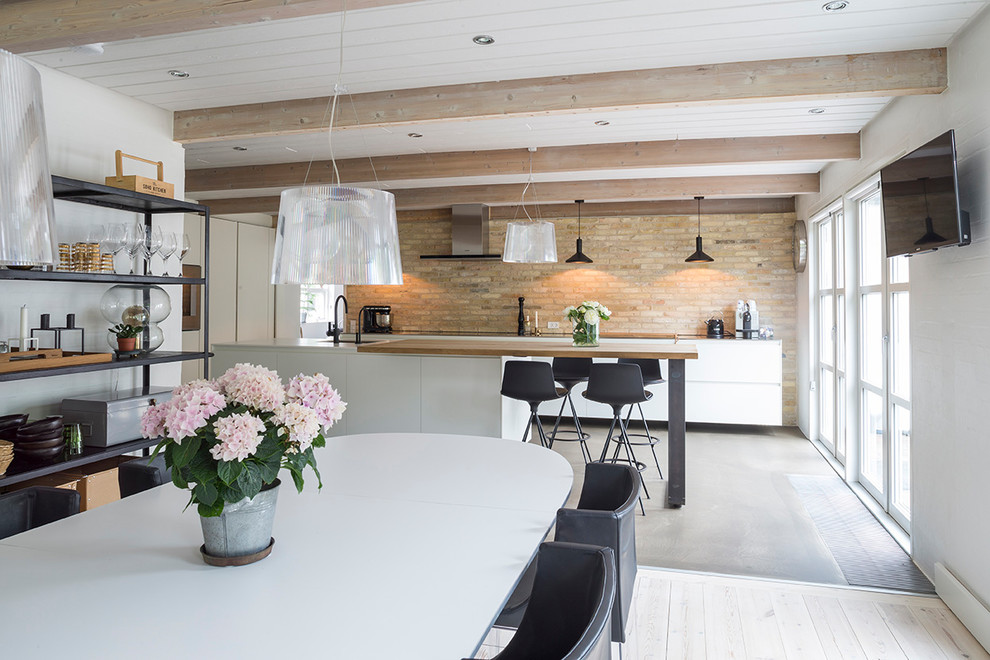 Large contemporary galley open plan kitchen in Esbjerg with an undermount sink, flat-panel cabinets, white cabinets, stainless steel benchtops, concrete floors, with island and grey floor.