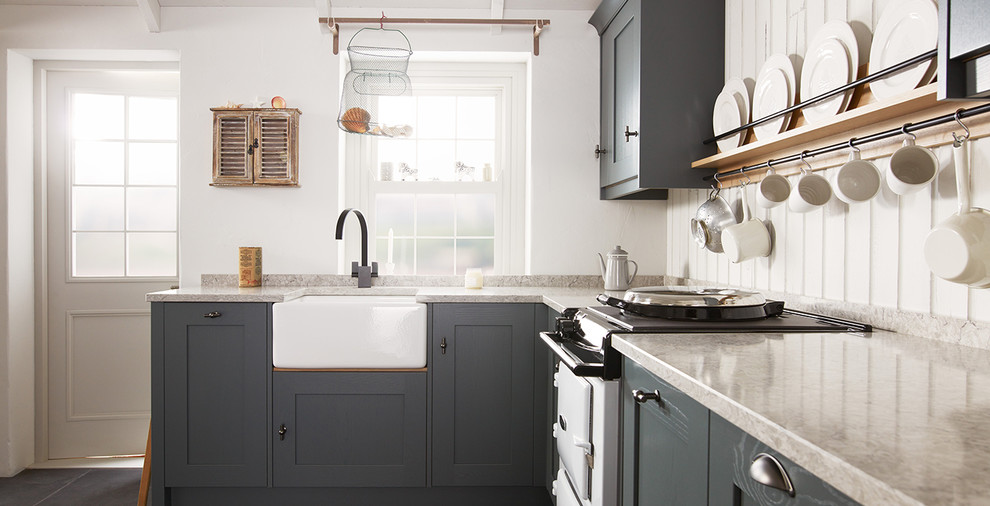 Design ideas for a mid-sized beach style l-shaped eat-in kitchen in Dublin with a farmhouse sink, shaker cabinets, distressed cabinets, solid surface benchtops, white appliances, ceramic floors, no island and timber splashback.