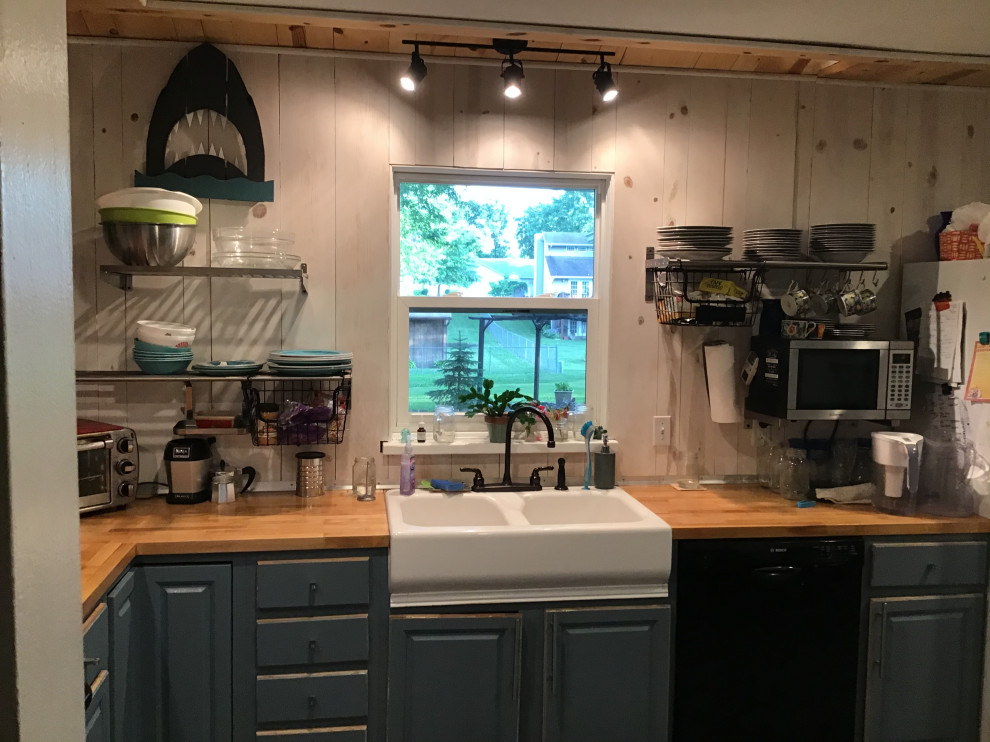 Mid-sized contemporary l-shaped eat-in kitchen in St Louis with a farmhouse sink, flat-panel cabinets, blue cabinets, wood benchtops, white splashback, timber splashback, black appliances, ceramic floors, with island, grey floor and multi-coloured benchtop.