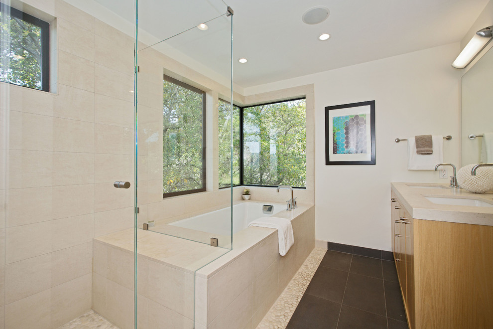 Photo of a mid-sized contemporary master bathroom in San Francisco with an undermount sink, flat-panel cabinets, medium wood cabinets, limestone benchtops, an undermount tub, an open shower, beige tile, stone tile, white walls and pebble tile floors.