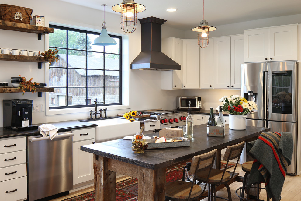 Country l-shaped kitchen in Grand Rapids with a farmhouse sink, shaker cabinets, white cabinets, window splashback, stainless steel appliances, light hardwood floors, with island and beige floor.