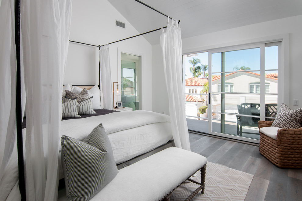 Large beach style master bedroom in Orange County with white walls and dark hardwood floors.