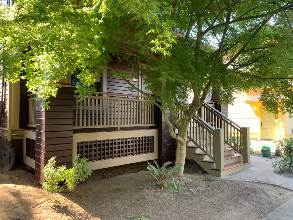 This is an example of a mid-sized traditional front yard verandah in Portland with a roof extension and wood railing.