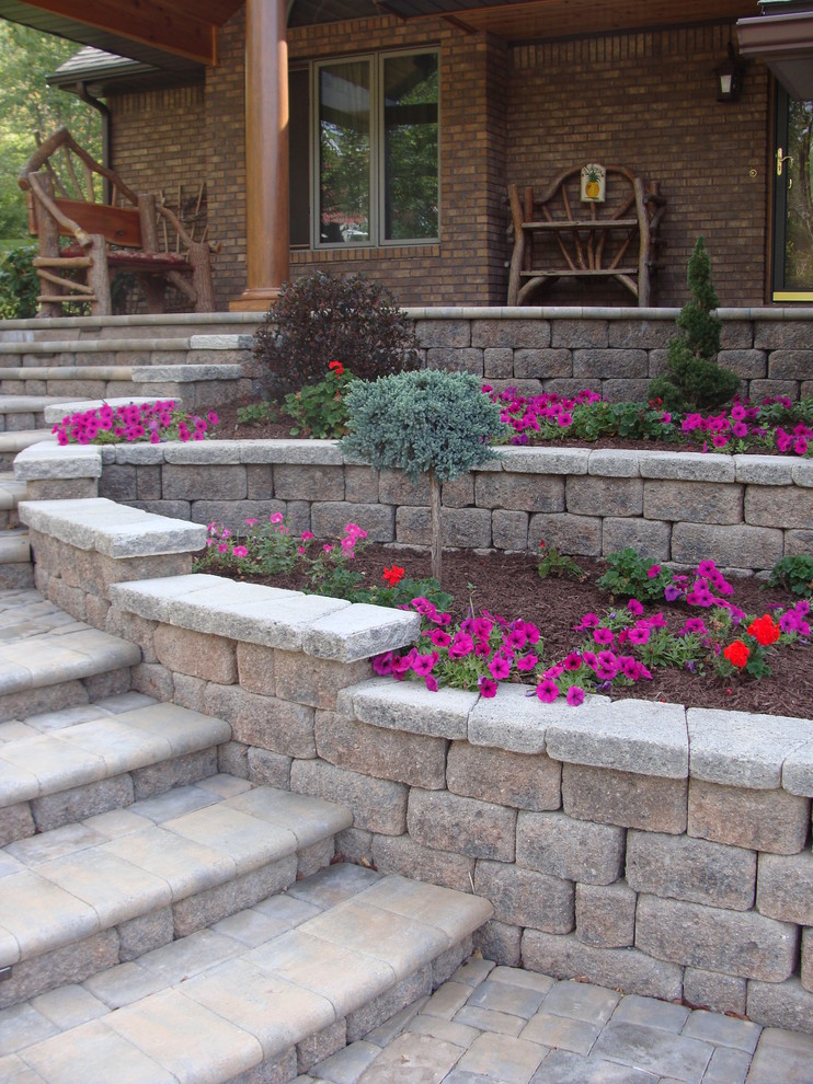 Mid-sized country front yard formal garden in Other with a retaining wall and concrete pavers.