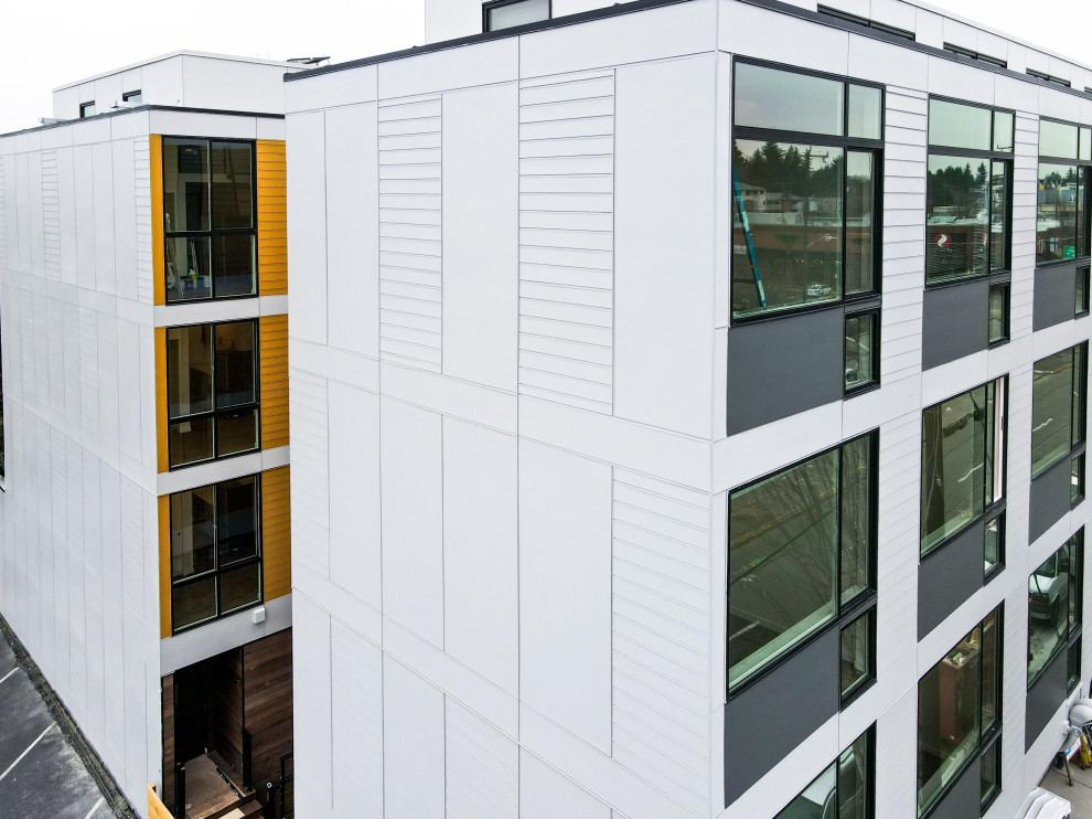 Foto della facciata di un appartamento grande bianco contemporaneo a quattro piani con rivestimento con lastre in cemento, tetto piano, copertura in metallo o lamiera, tetto grigio e pannelli e listelle di legno