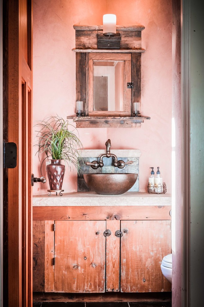 Small country powder room in New York with a vessel sink, flat-panel cabinets, medium wood cabinets and pink walls.