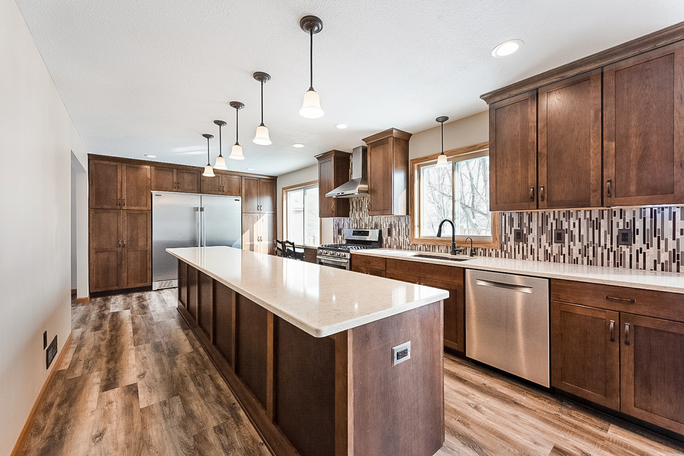 Mid-sized arts and crafts galley eat-in kitchen in Minneapolis with an undermount sink, shaker cabinets, dark wood cabinets, quartz benchtops, multi-coloured splashback, mosaic tile splashback, stainless steel appliances, vinyl floors, with island, multi-coloured floor and beige benchtop.