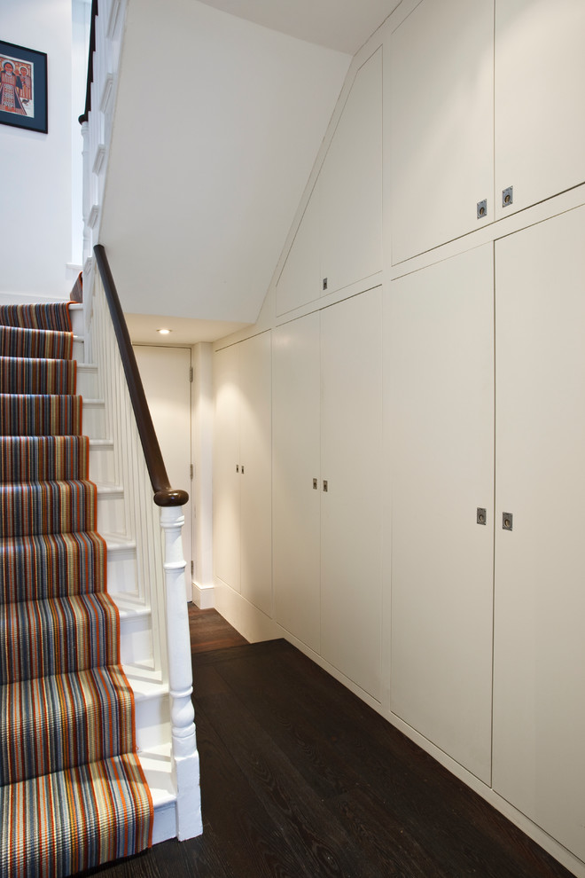 This is an example of a contemporary hallway in London with white walls and dark hardwood floors.