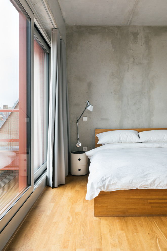 Photo of a contemporary bedroom in Berlin with grey walls and medium hardwood floors.
