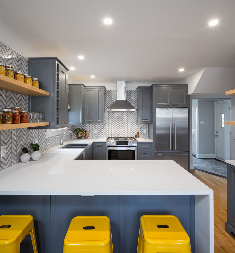Mid-sized transitional l-shaped eat-in kitchen in Ottawa with an undermount sink, recessed-panel cabinets, blue cabinets, quartz benchtops, grey splashback, stone tile splashback, stainless steel appliances, light hardwood floors and no island.