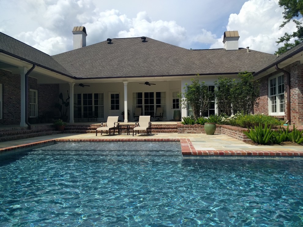 Mid-sized traditional backyard rectangular lap pool in New Orleans with a hot tub and natural stone pavers.