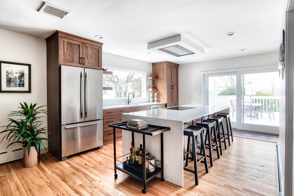 Mid-sized transitional galley kitchen in New York with an undermount sink, shaker cabinets, medium wood cabinets, quartzite benchtops, white splashback, stainless steel appliances, with island, white benchtop, medium hardwood floors and brown floor.