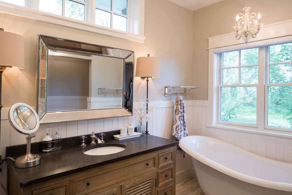 Mid-sized traditional master bathroom in Other with distressed cabinets, a claw-foot tub, beige walls, an undermount sink, brown floor, louvered cabinets, porcelain floors, soapstone benchtops and black benchtops.