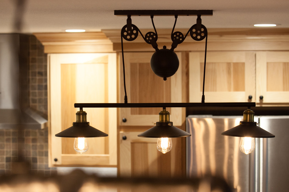 Mid-sized mountain style l-shaped medium tone wood floor eat-in kitchen photo in Seattle with a farmhouse sink, shaker cabinets, light wood cabinets, quartz countertops, beige backsplash, stone tile backsplash, stainless steel appliances and an island