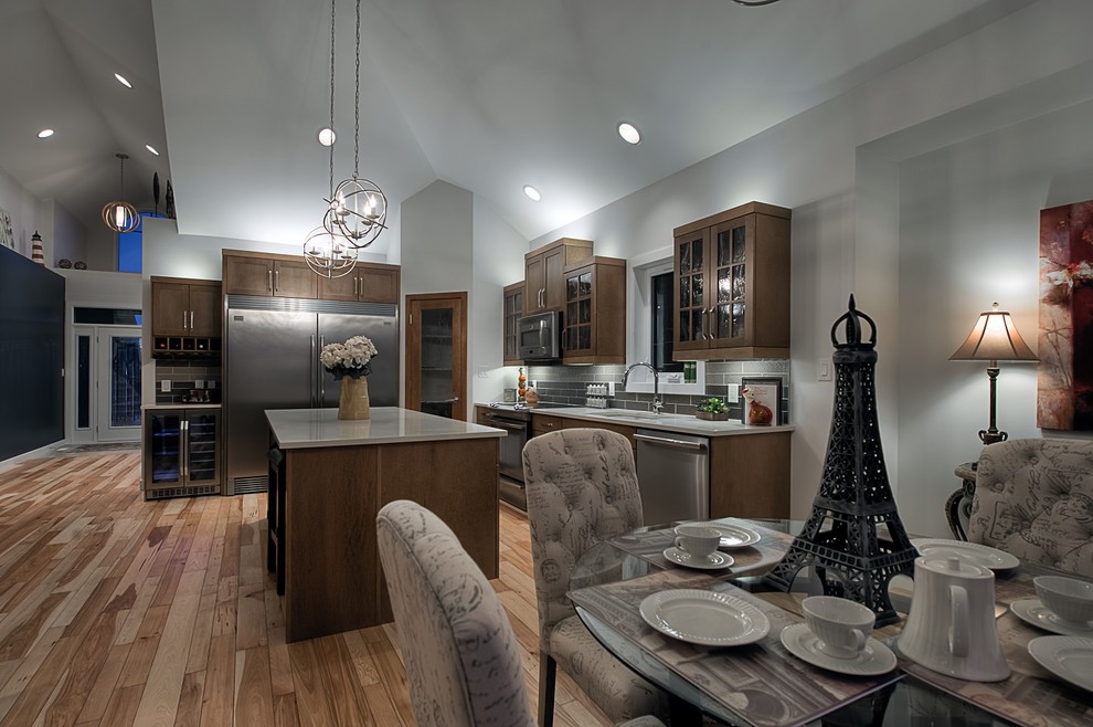 Example of a mid-sized transitional l-shaped medium tone wood floor eat-in kitchen design with an undermount sink, shaker cabinets, medium tone wood cabinets, quartz countertops, brown backsplash, glass tile backsplash, stainless steel appliances and an island