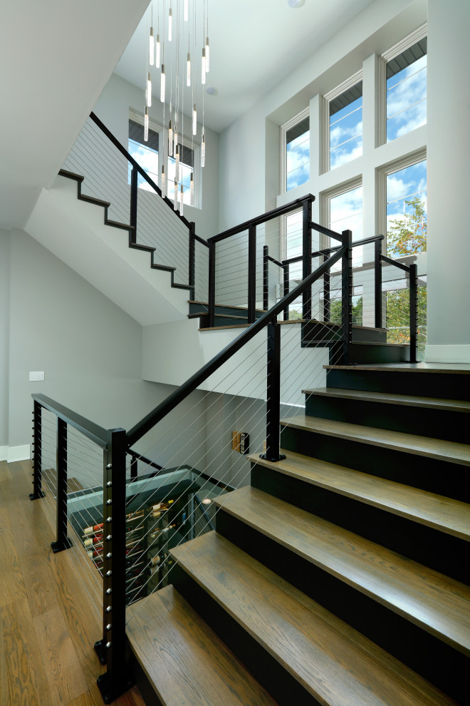 This is an example of a large transitional wood u-shaped staircase in Grand Rapids with wood risers and metal railing.