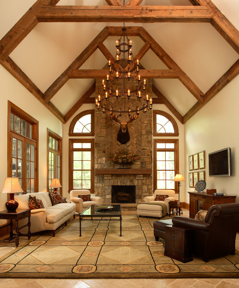 This is an example of a country enclosed family room in Atlanta with beige walls, travertine floors, a standard fireplace, a stone fireplace surround, a wall-mounted tv and beige floor.