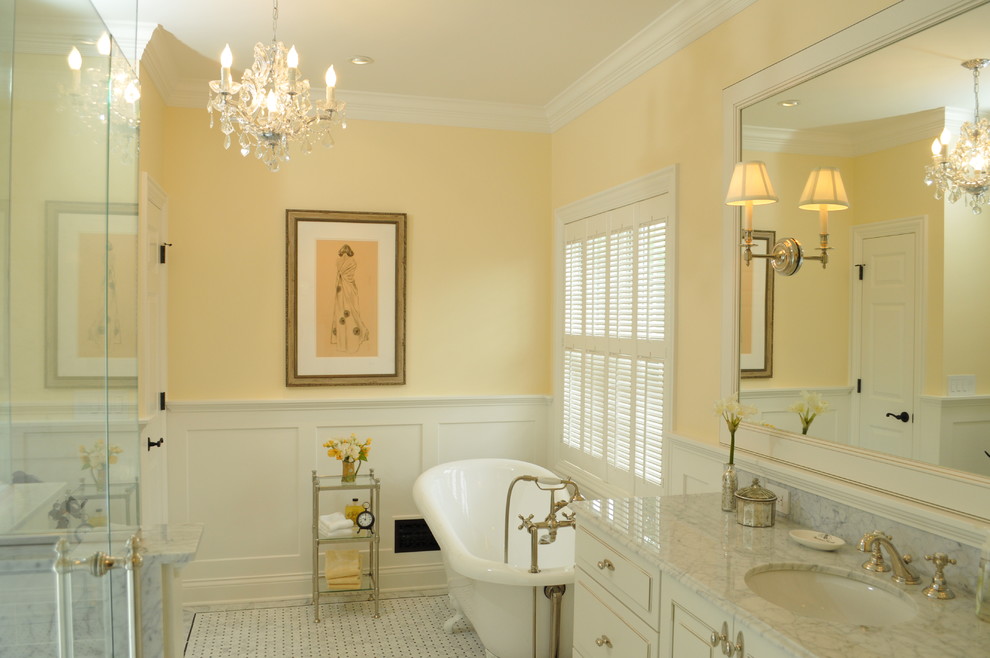 Photo of a mid-sized traditional bathroom in San Francisco with an undermount sink, raised-panel cabinets, white cabinets, marble benchtops, a claw-foot tub, a two-piece toilet, white tile, stone tile, yellow walls and marble floors.