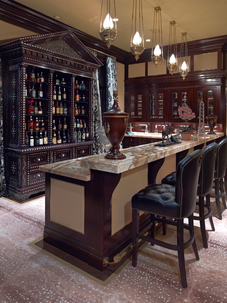 This is an example of a traditional l-shaped seated home bar in Dallas with carpet, glass-front cabinets and dark wood cabinets.