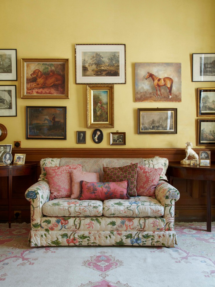 This is an example of a country living room in London with yellow walls and dark hardwood floors.
