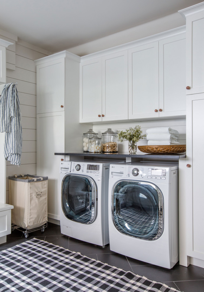 Photo of a mid-sized mediterranean u-shaped dedicated laundry room in Jacksonville with a single-bowl sink, shaker cabinets, white cabinets, quartz benchtops, white splashback, shiplap splashback, white walls, porcelain floors, a side-by-side washer and dryer, black floor, black benchtop and planked wall panelling.
