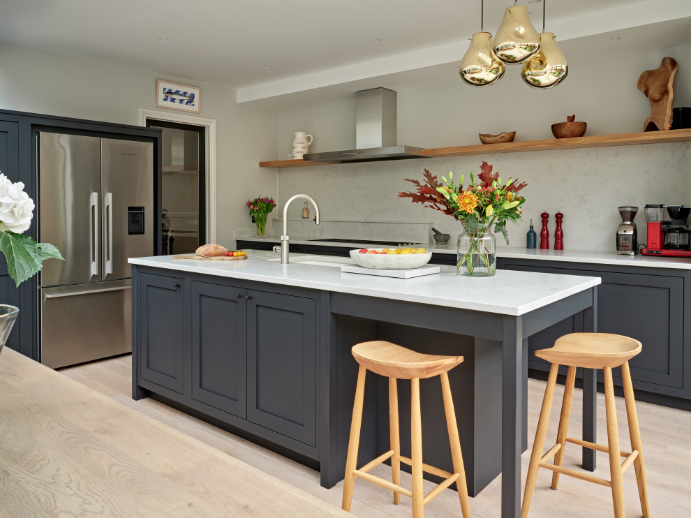 Inspiration for a large transitional single-wall eat-in kitchen in London with an undermount sink, shaker cabinets, black cabinets, quartzite benchtops, white splashback, engineered quartz splashback, stainless steel appliances, with island and white benchtop.